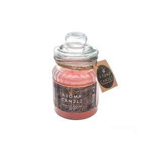 A pink scented jar candle in a glass jar with a lid and a label attached reading Aroma Candle. Image relates to a product titled: شمع معطر لیوانی هی وود دی‌اسکوئرد (Dsquared2 He Wood)